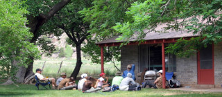 Staff and students sit on grass outside a building at Range Creek.