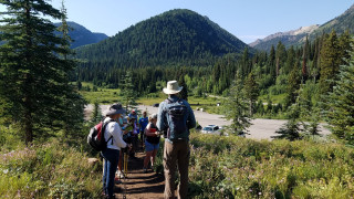 A group of teachers on a trail with wooded mountains in the background