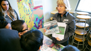 NHMU Volunteer Jane Yager works with a group of field trip students at the Museum.