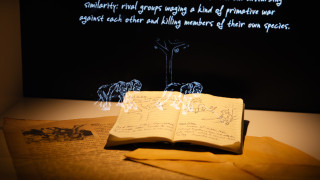 A projection overlays a physical book in a case in the Becoming Jane exhibit. 