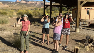 A group of teachers in an outdoor classroom using binoculars
